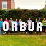 Group of Horbury residents standing in a green space, holding large white HORBURY letters